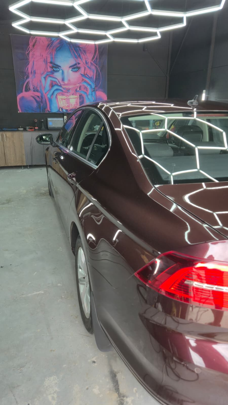 Spatele aceleiași mașini după polish, sub lampa hexagonală: liniile lămpii se reflectă subțiri și continue pe aripă și pe capacul portbagajului, fără halou în jurul lor.